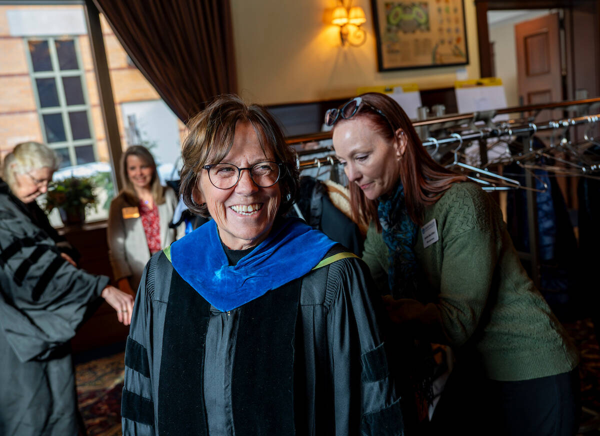 Theresa Bacon-Baguley smiles as Justine Rau Kibet helps during robing at the Faculty Awards Convocation in February, when Bacon-Baguley earned a Niemeyer Award.